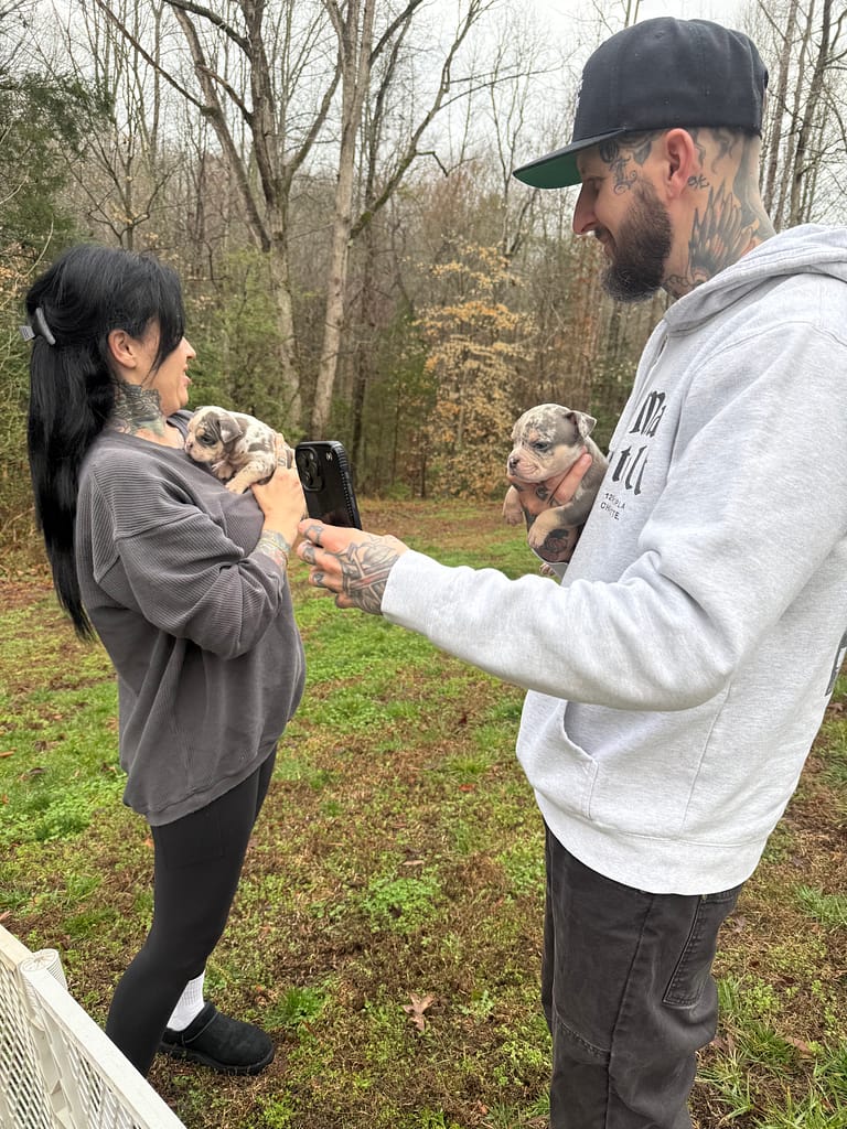 Zahra and Matt holding two different micro bully puppies during the surprise visit at Southeast Bully Kennels as they decided which puppy would become Matt’s birthday gift.