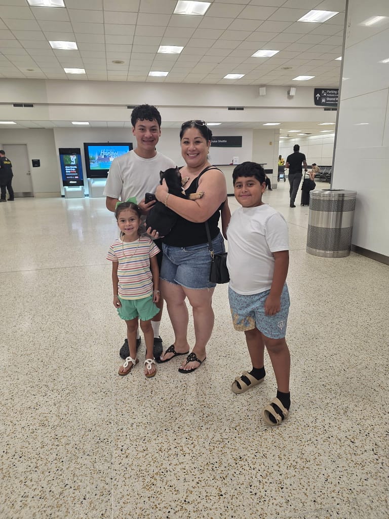 Luis Ochoa's family in Houston meeting their trained black and tan female micro bully puppy at the airport delivered by Southeast Bully Kennels.